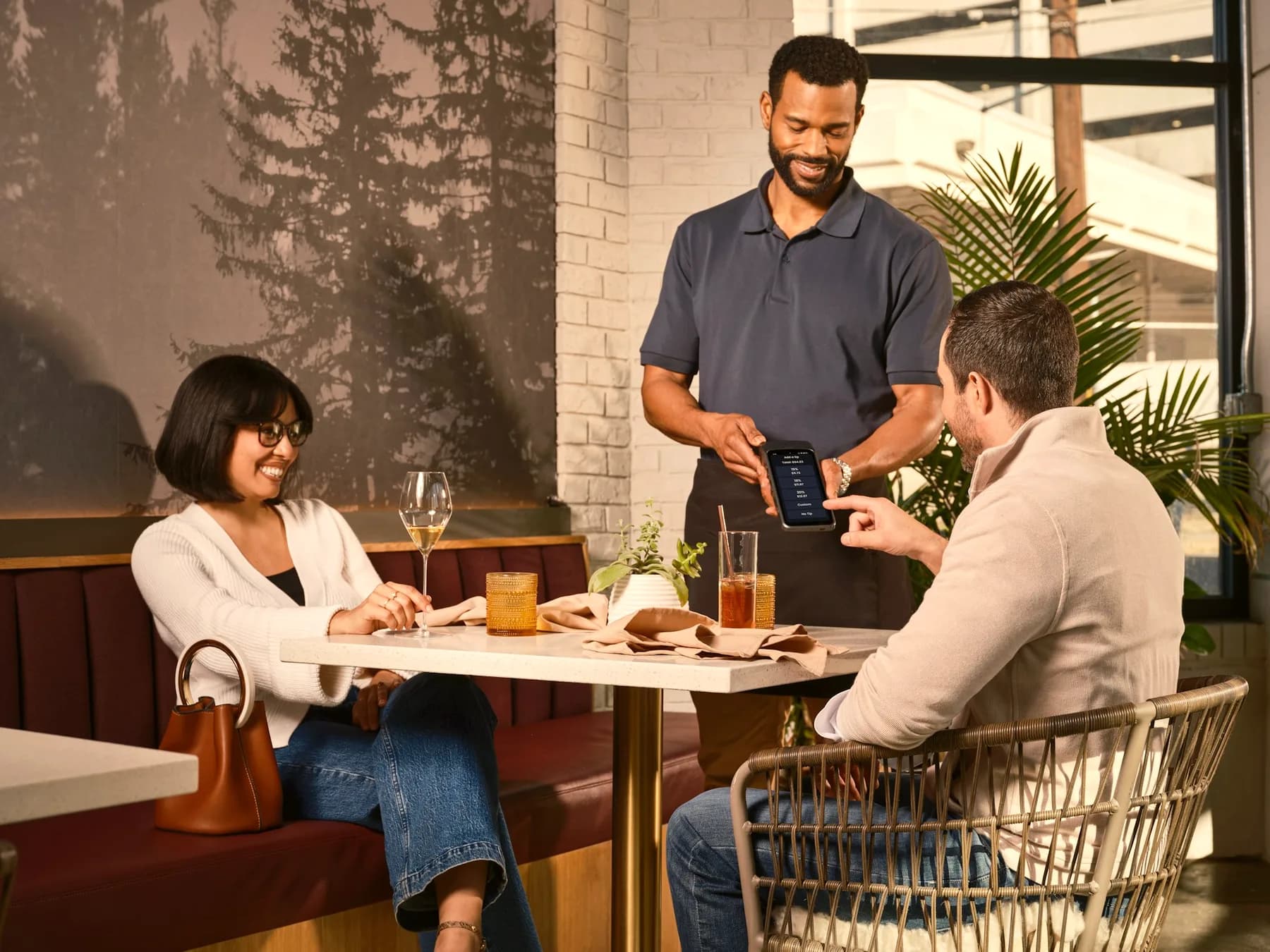 A waiter showing the bill on a handheld device to guests